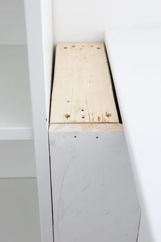 an unfinished piece of wood sitting on top of a white shelf