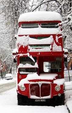 a red double decker bus covered in snow