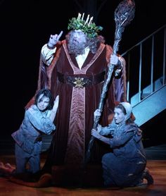 the wizard is standing on stage with his staff and two children in front of him