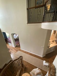 an overhead view of a living room and staircase in a home with wood floors, white walls and metal railings