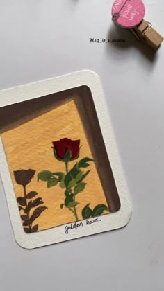 a red rose sitting on top of a white table next to a rubber pad with the word golden house