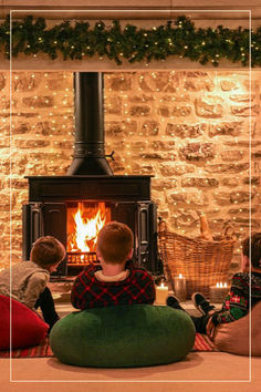 two children sitting on bean bag chairs in front of a fireplace with lit christmas lights