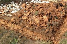 a pile of dirt sitting next to a building on top of a grass covered field