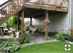 a backyard with a hammock in the middle and some plants on the other side