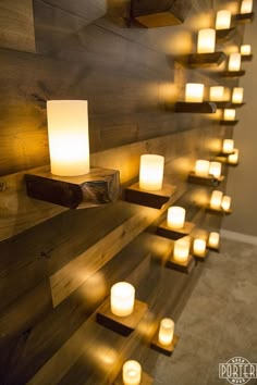 many lit candles are placed on the wall next to some wood planks and lights