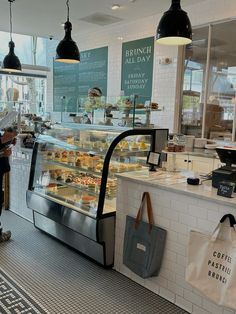 a woman standing in front of a display case filled with pastries and desserts