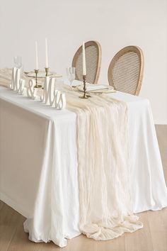 the table is set with white linens and candles