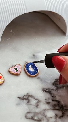 a woman is painting decorated cookies on the counter with a paintbrush in her hand