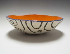 an orange and white bowl with black designs on it