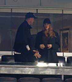 a man and woman standing next to each other in front of an empty bleachers