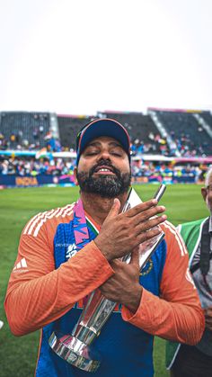 a man holding a trophy while standing on top of a field