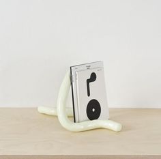 a white book holder sitting on top of a wooden table next to a white wall