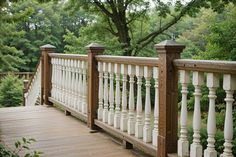 a wooden bridge with white railings surrounded by trees