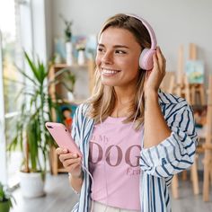 a young woman listening to music while holding a pink phone and headphones in her hands