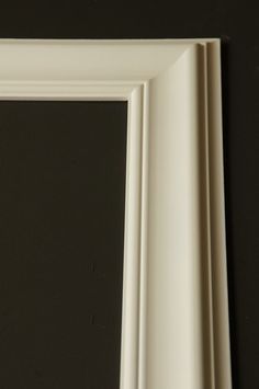 an empty white frame on a black wall