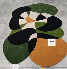 an area rug with different colors and shapes on the floor in front of a tile floor