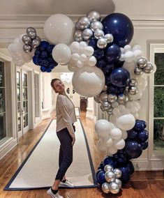 a woman standing under a bunch of balloons