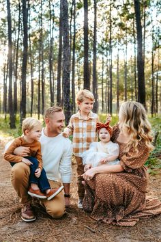 a family sitting in the woods with their two children and one is wearing a bow tie