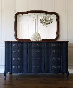 a blue dresser with a mirror and chandelier on it's sideboard