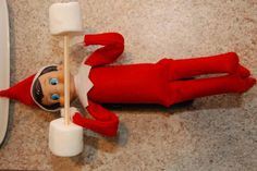 an elf is laying on the floor with marshmallows in front of him