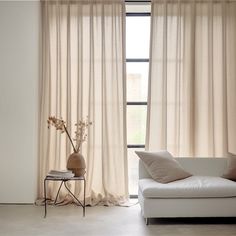 a white couch sitting next to a window covered in curtains