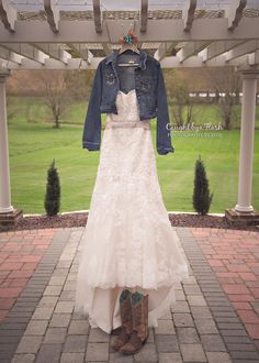 a wedding dress and cowboy boots are on display in front of an open gazebo