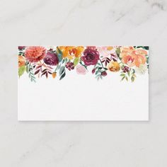 a card with flowers on it sitting on top of a white tablecloth next to a marble wall