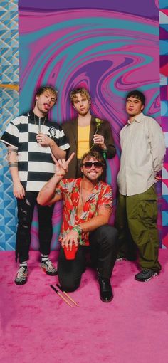 four young men posing for a photo in front of a colorful background