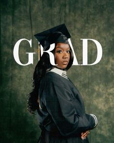 a woman wearing a graduation cap and gown standing in front of a grad sign