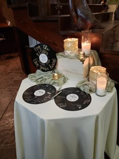 a table topped with two tiered cake covered in cd's and lit candles