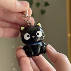 a person holding a black cat keychain in their hand