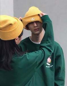 a young man and woman wearing yellow hats are looking into each other's eyes