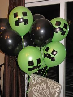 a bunch of black and green balloons in the shape of smiley faces on a chair