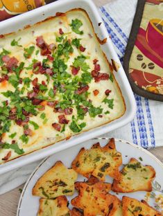 a casserole dish with bacon, cheese and chives next to other appetizers