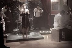 a group of people that are standing in front of a piano and some microphones