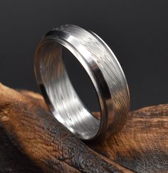 a wedding ring sitting on top of a piece of wood with silver inlays