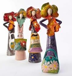 three ceramic figurines are standing next to each other, one holding a handbag and the other carrying a purse