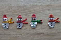 three beaded snowmen sitting on top of a wooden table