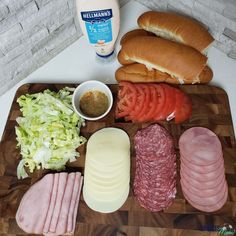 a cutting board topped with meats, cheese and bread