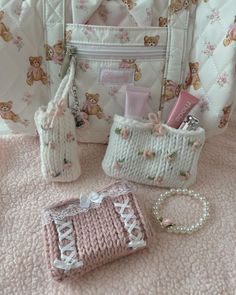 the contents of a purse and handbag are laid out on a pink blanket with teddy bears