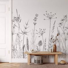 a room with a bench, vases and flowers on the wall next to it