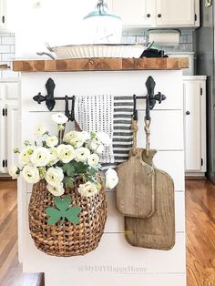 a kitchen with white cabinets and wooden flooring is pictured in this image, there are cutting boards hanging on the wall