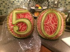 two carved watermelon numbers sitting on top of a counter next to a sink