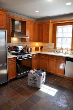 an empty kitchen with stainless steel appliances and wood cabinets, including a dishwasher