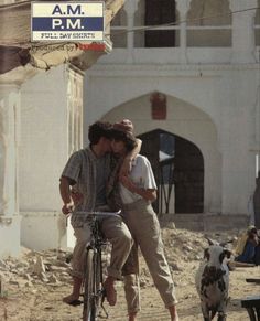 two people on a bike in front of a building