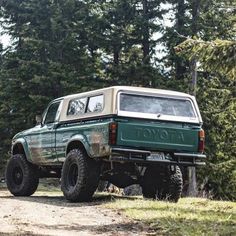 a green truck parked on top of a dirt road