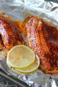 two fish fillets on foil with lemon slices