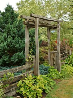 an old wooden arbor in the middle of a garden