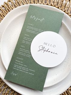 a white plate topped with a menu and a green paper place card on top of it