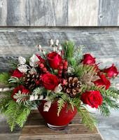 a red vase filled with flowers on top of a wooden table